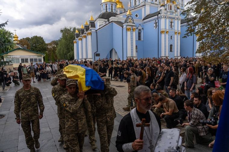 A pregnant soldier mourns her 21-year-old husband at his funeral in Ukraine